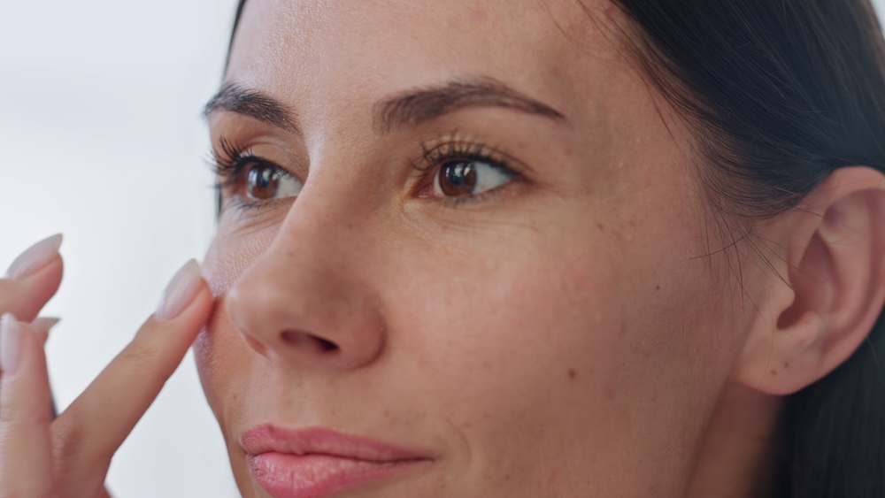 A happy woman looking at her face after dermal fillers