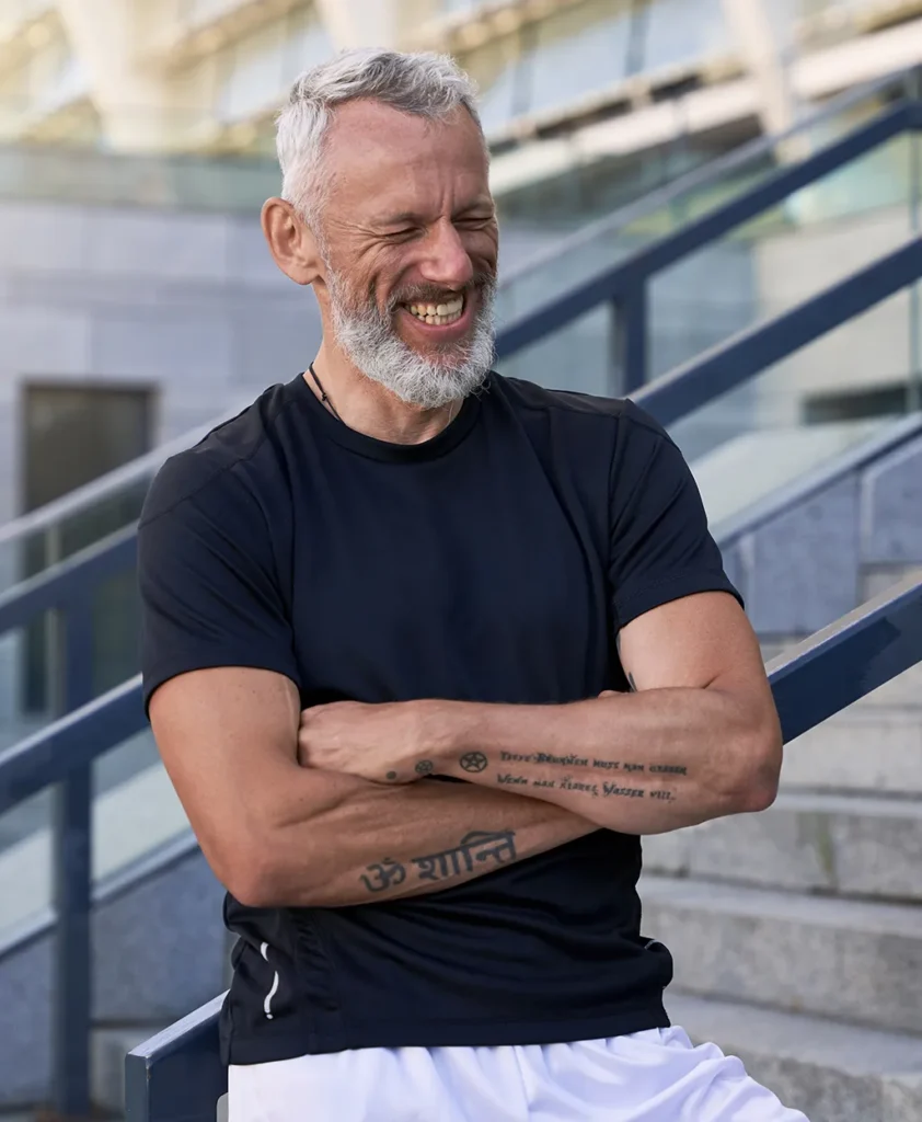 Testosterone Replacement Therapy | Mature man leaning on rail with arms crossed and smiling